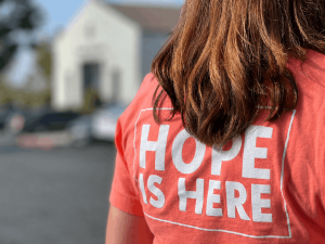 Love Life sidewalk team member wearing a Hope Is Here shirt outside an abortion center