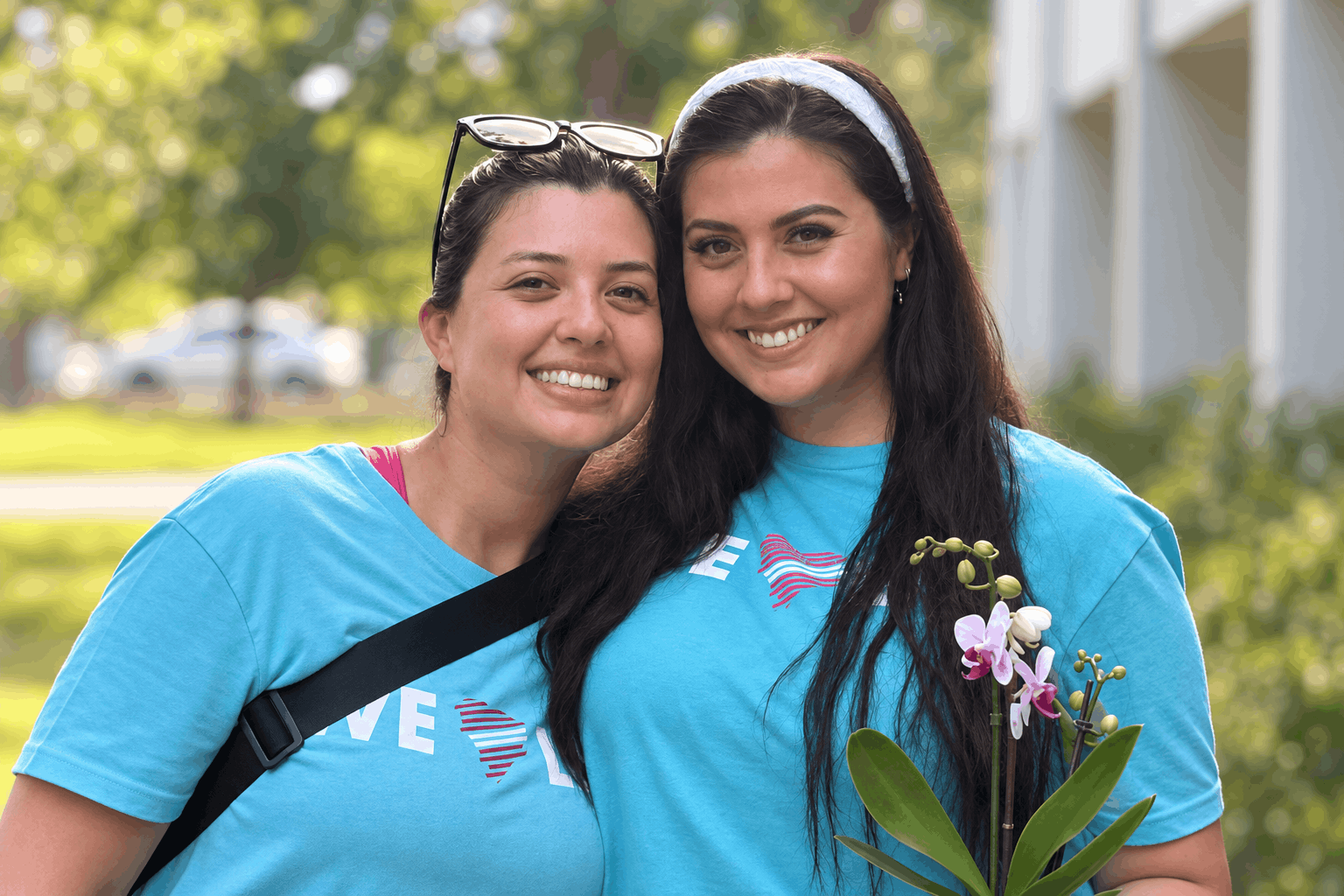Two women in Love Life shirts stand together outdoors